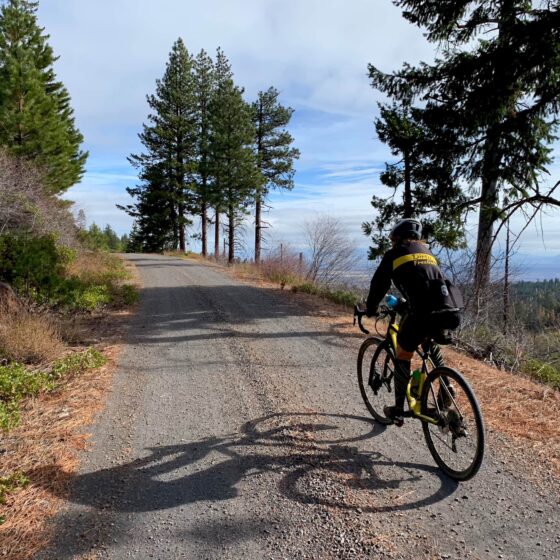 Gravel bike rider on hard pack gravel road with open view to the east.
