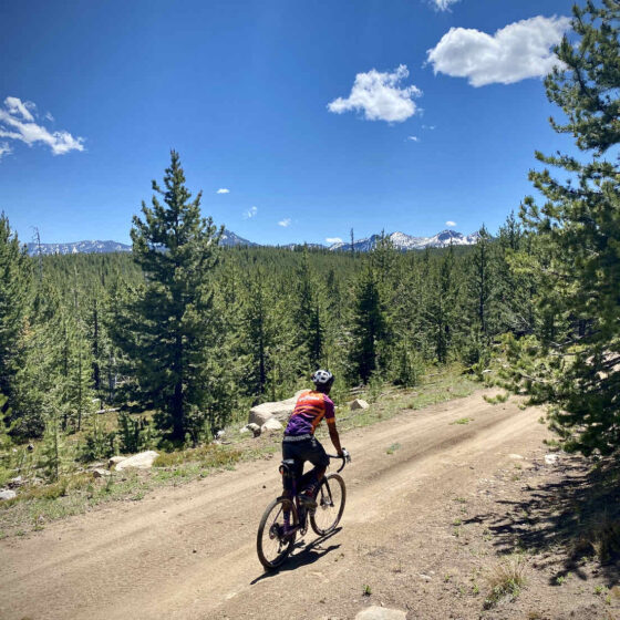 cyclist climbs a gravel hill with mountain views