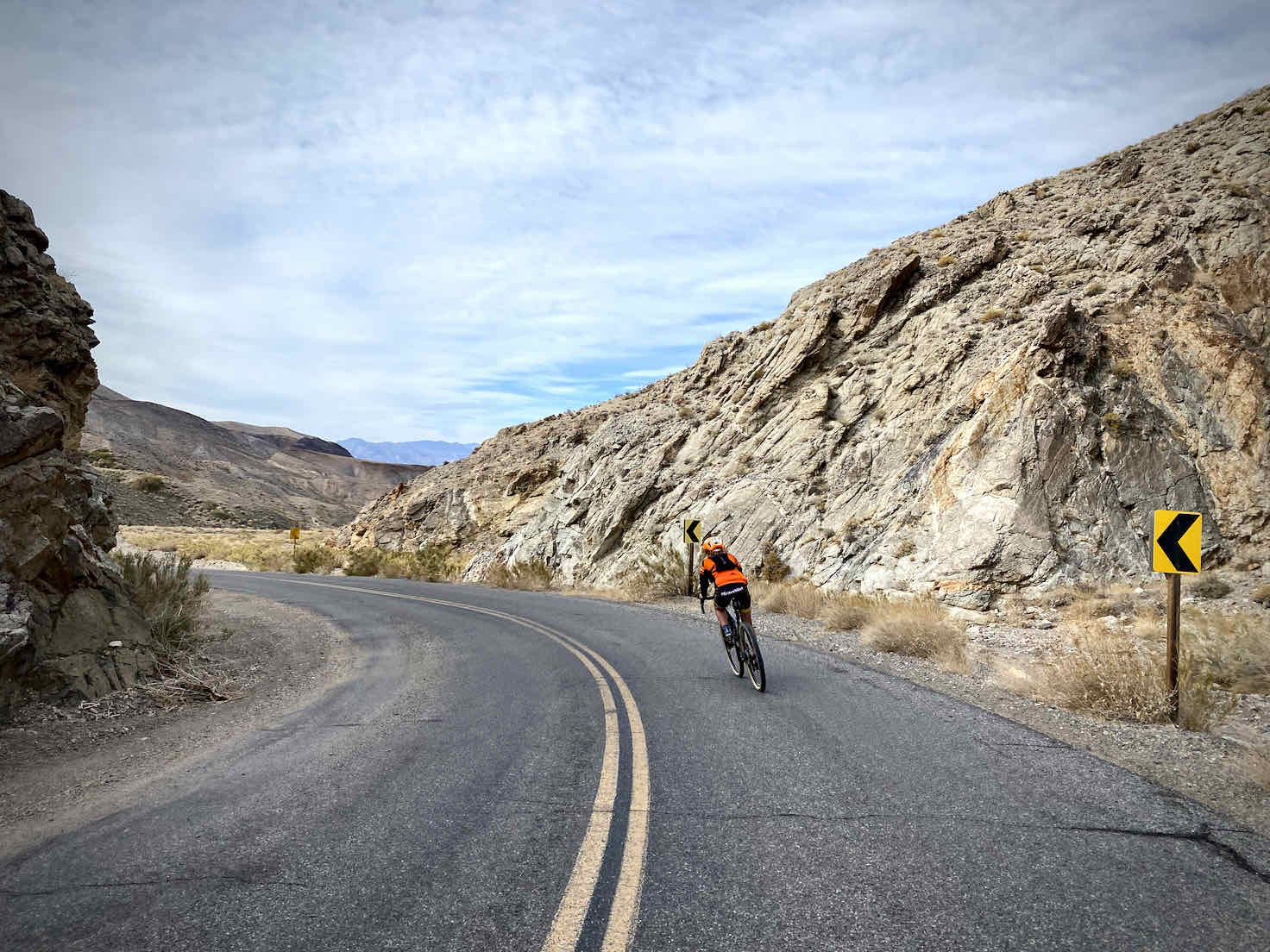 Cyclist making fast bending left hand turn on paved road in Death Valley National Park.