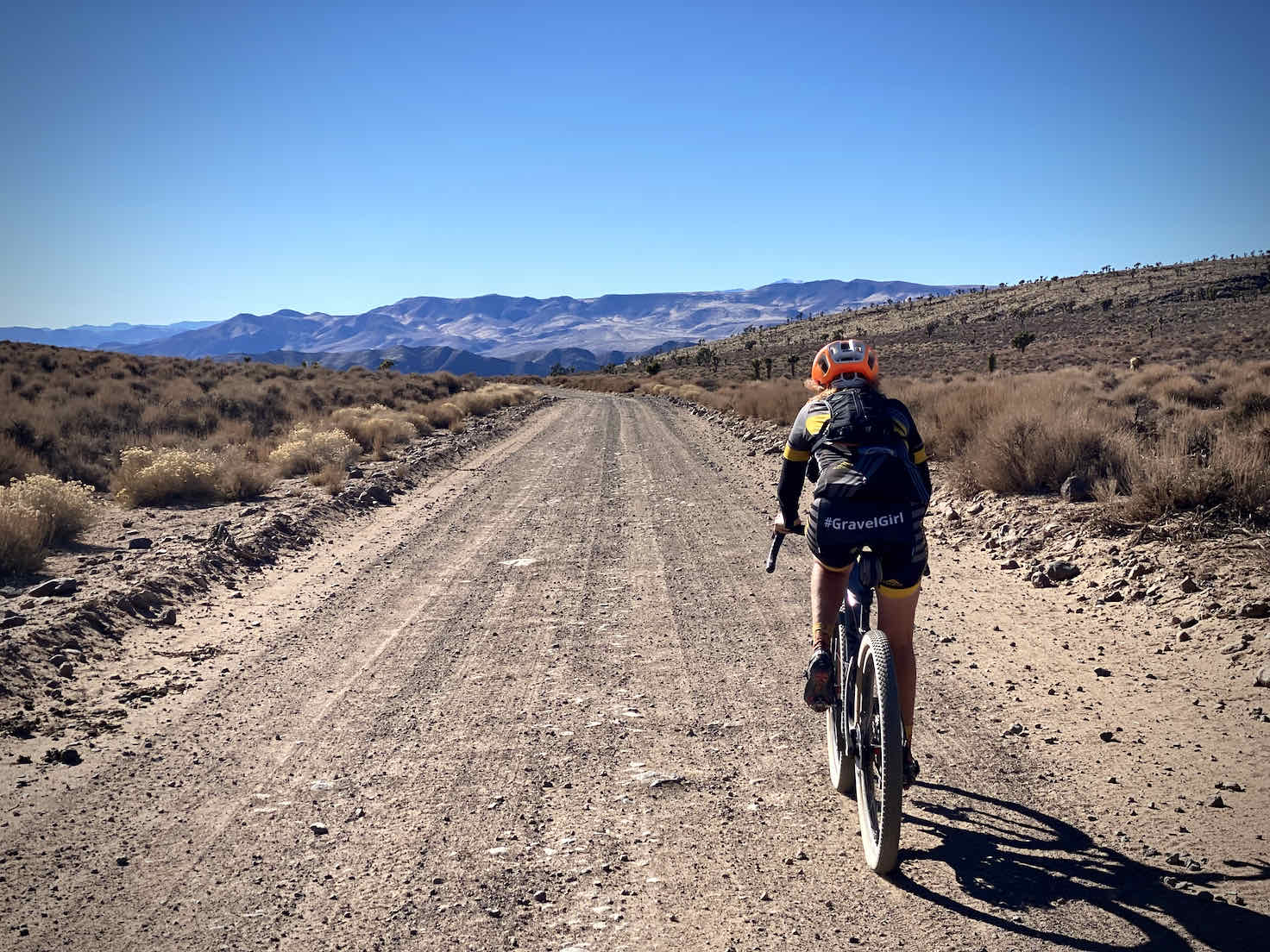 Woman gravel cyclist descending back into Lee's Flat and the Joshua Trees.