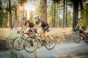 Two bike riders on gravel road.