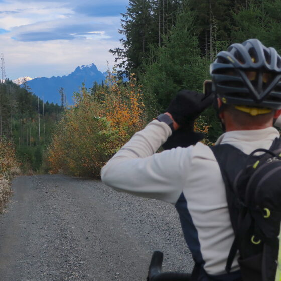 Cyclist stopping to photograph Glacier and Whitehorse peaks