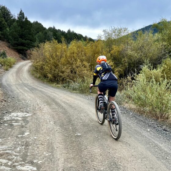 Sweeping gravel road along a creek with cyclist.