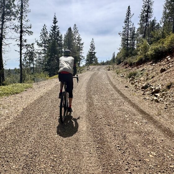 Gravel cyclist on red gravel road.