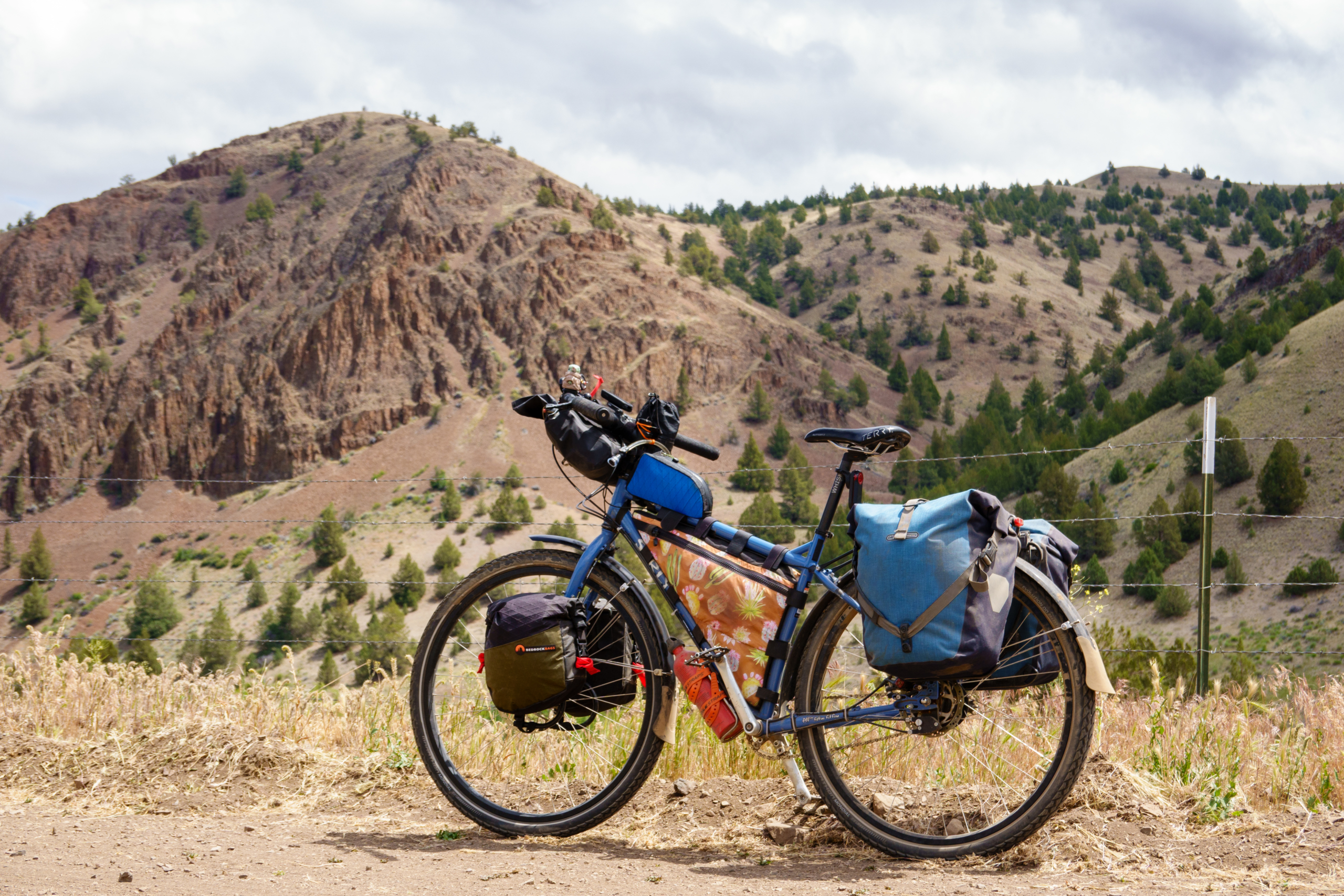 Bikepacker riding the Oregon Outback gravel road through sagebrush under big Oregon sky
